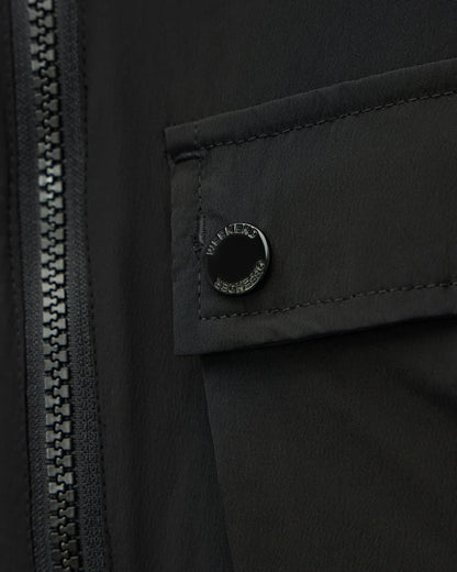 Close-up of a black jacket featuring a zippered front and a flap pocket with a circular black snap button engraved with 'MILITARY SPECIAL PURPOSE'.